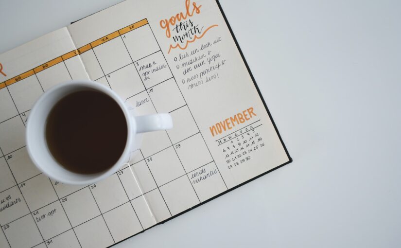 white ceramic mug with coffee on top of a planner